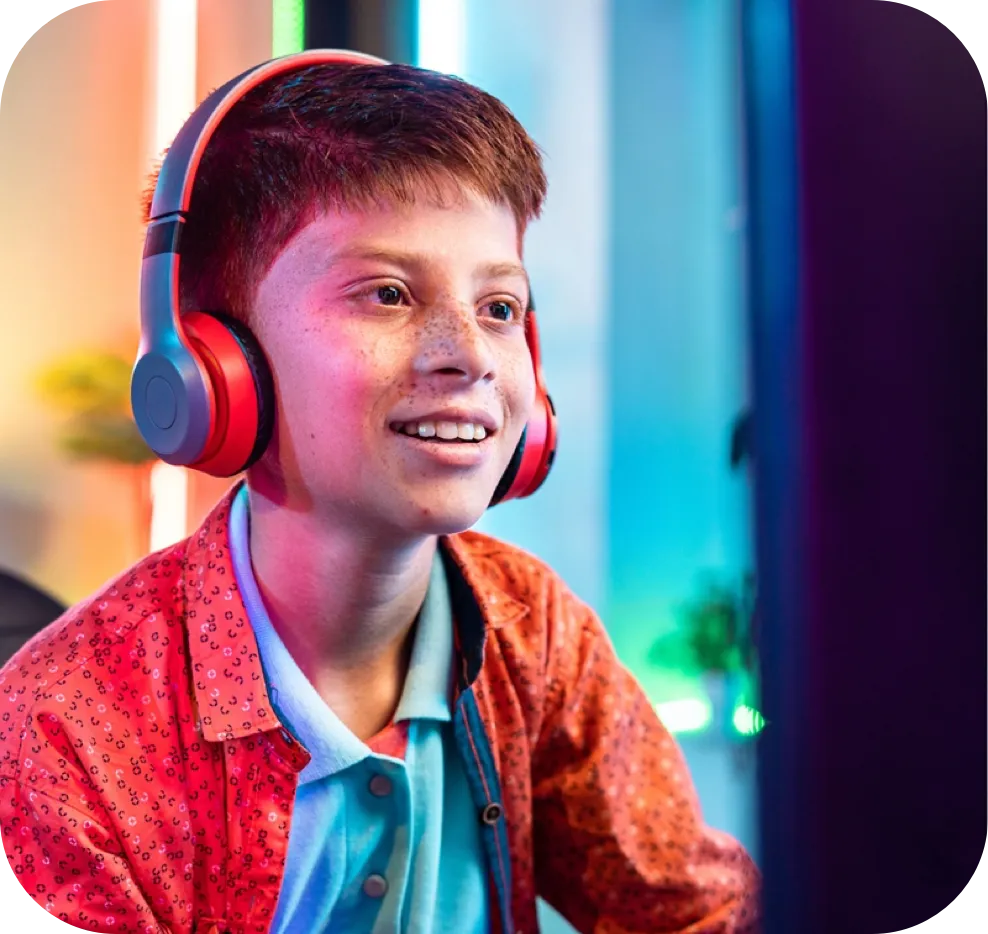 A boy with headphones looking at a computer screen.